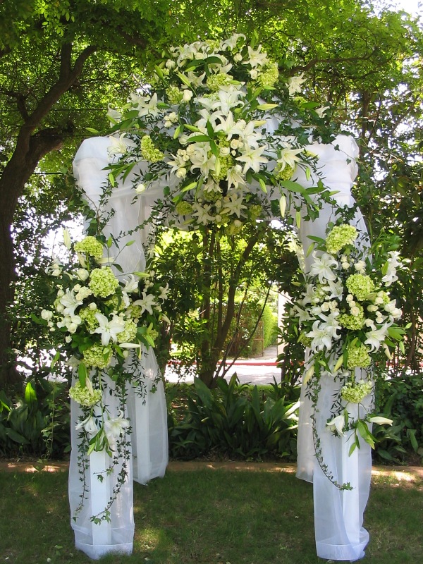 Silk fabric draped arbor with fresh floral badges